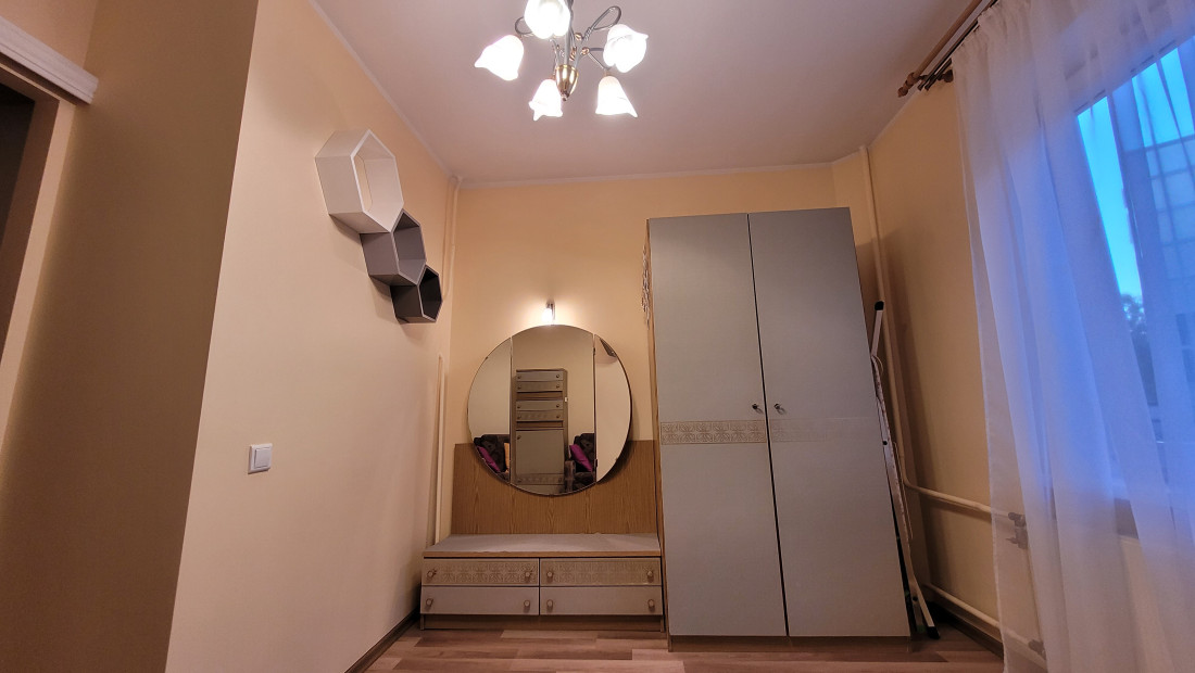 Bedroom with round mirror and wardrobe.