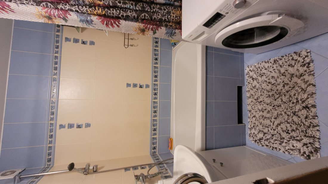  Bathroom with blue tiles and a washing machine.