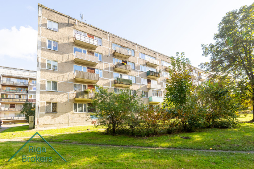 Piecstāvu māja ar balkoniem un kokiem.