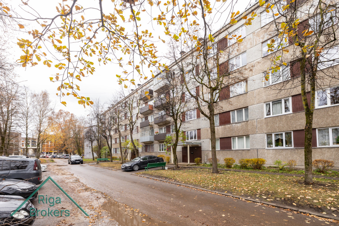 Piecstāvu ēka rudenīgā ainavā.