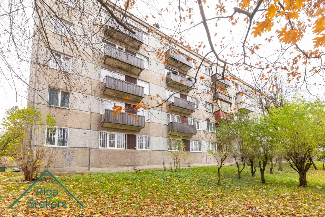 Ēka ar balkoniem un zālāju priekšā.