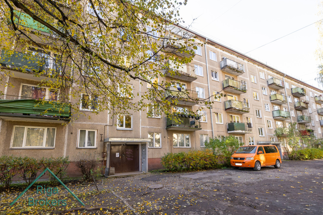 Residential building with an orange car in front.