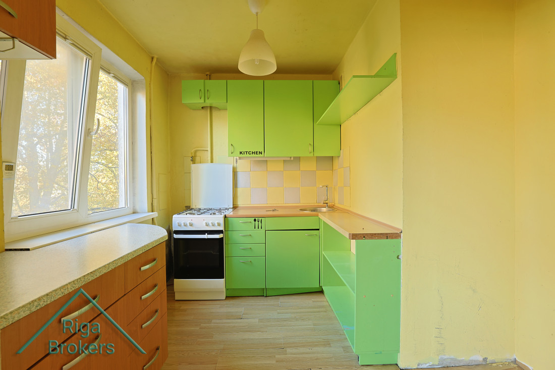 Green kitchen with wooden cabinets and gas stove.