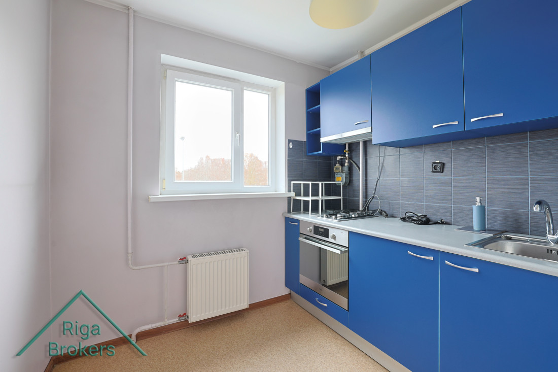 Kitchen with blue furniture and window.