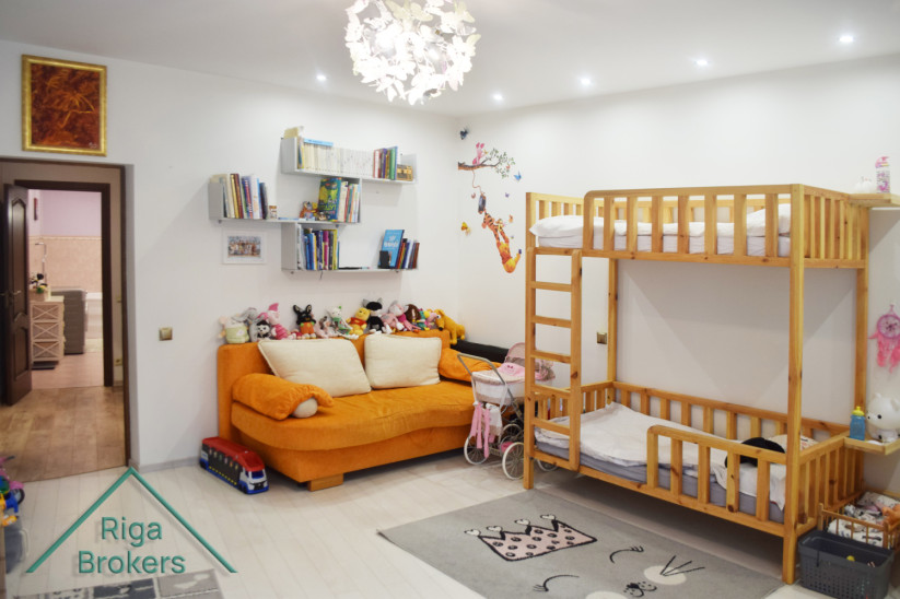 Children's room with bunk bed and orange sofa.