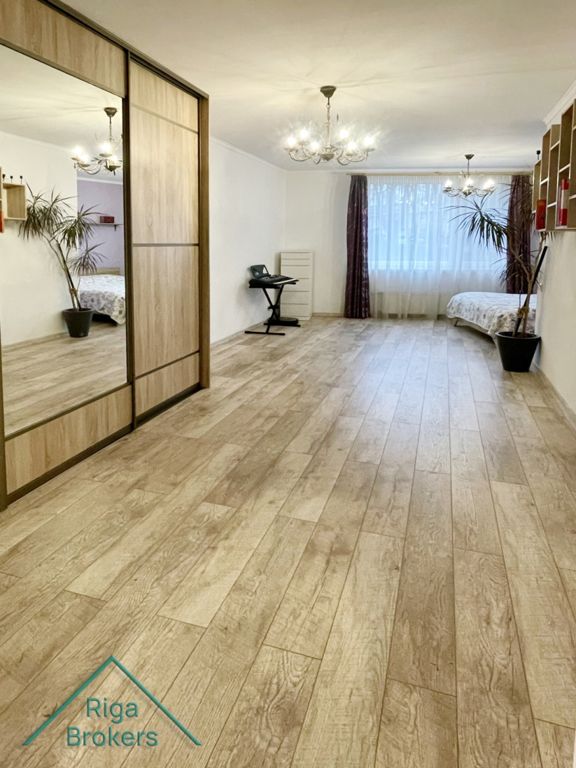 Spacious bedroom with mirrored wardrobes and window.
