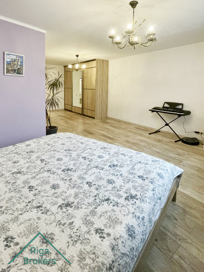 Spacious bedroom with piano and large window.