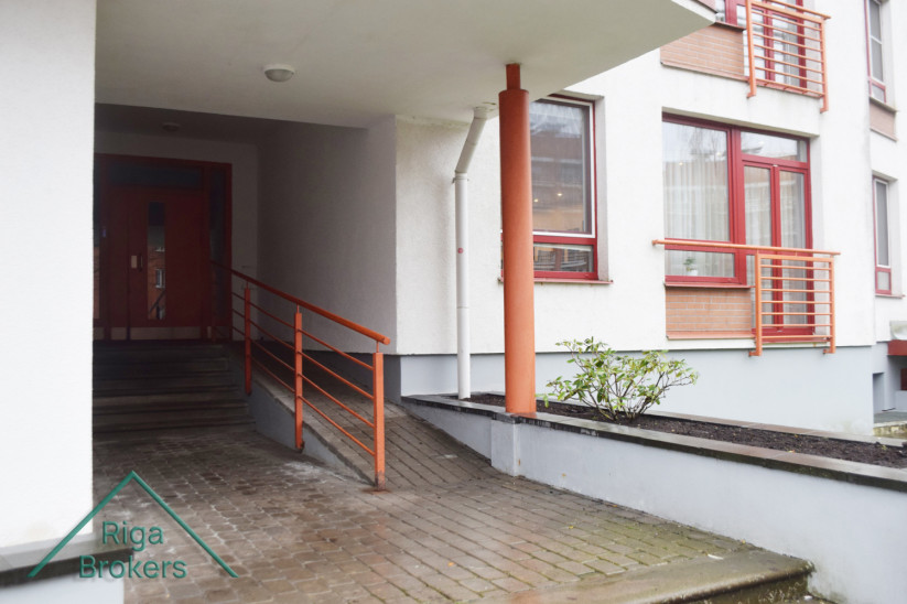 Apartment entrance with orange railings and steps.