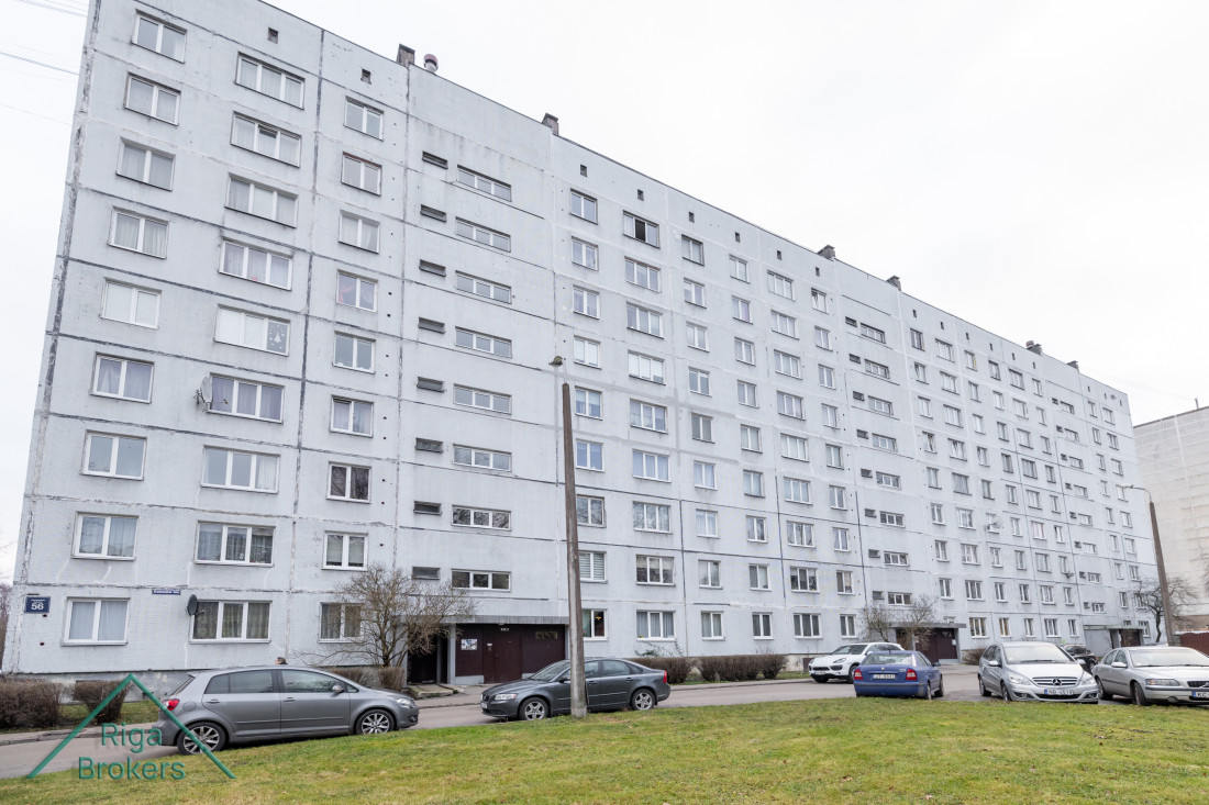 Apartment building with parking lot in front.