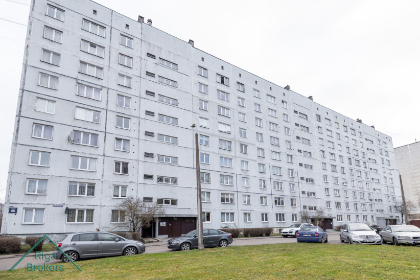 Apartment building with parking lot in front.