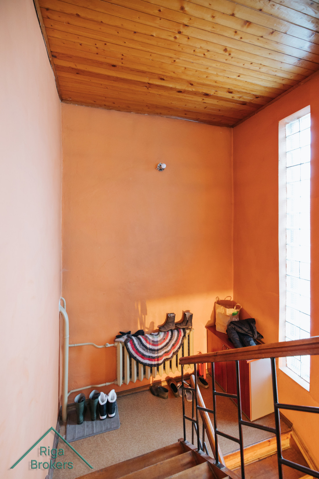 Orange hallway with shoes by the wall.