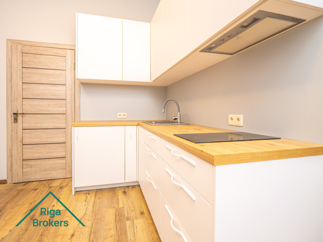 White kitchen furniture, wooden countertop, induction stove, extractor, door.