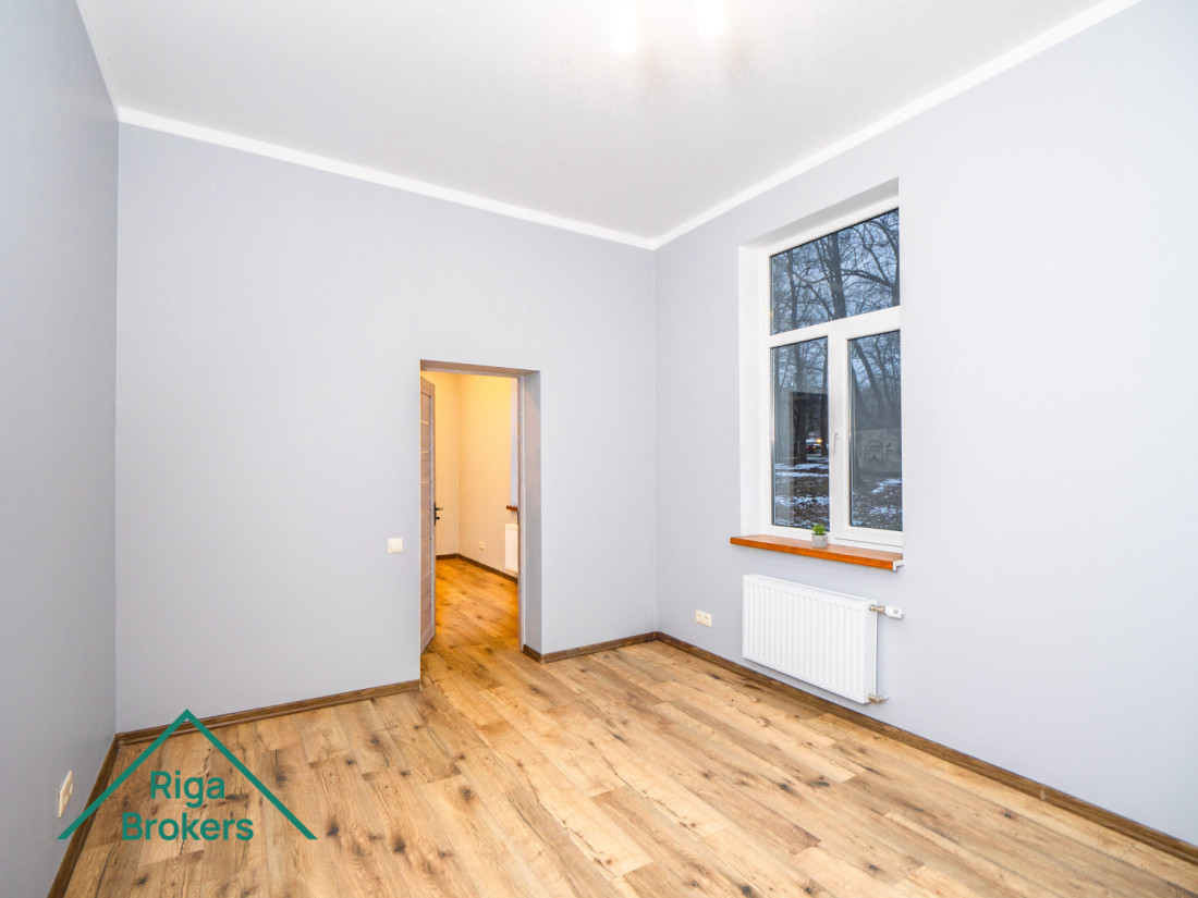 Bright room, wooden floor, large windows, modern interior.