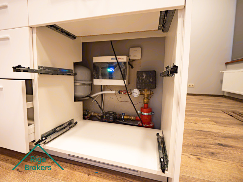 Compact water supply system in cabinet.Filters and pump installed inside.Red safety valve is visible.Wires connected to devices.Cabinet doors have mechanisms attached.