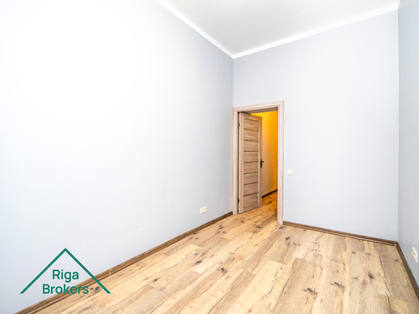 Bright room, wooden floor, large windows, modern interior.