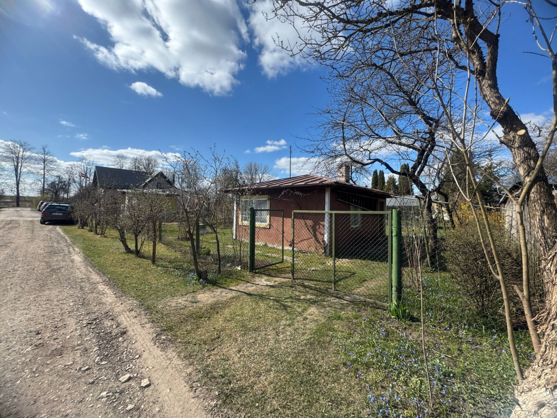 Māja ar metāla jumtu pie ceļa.