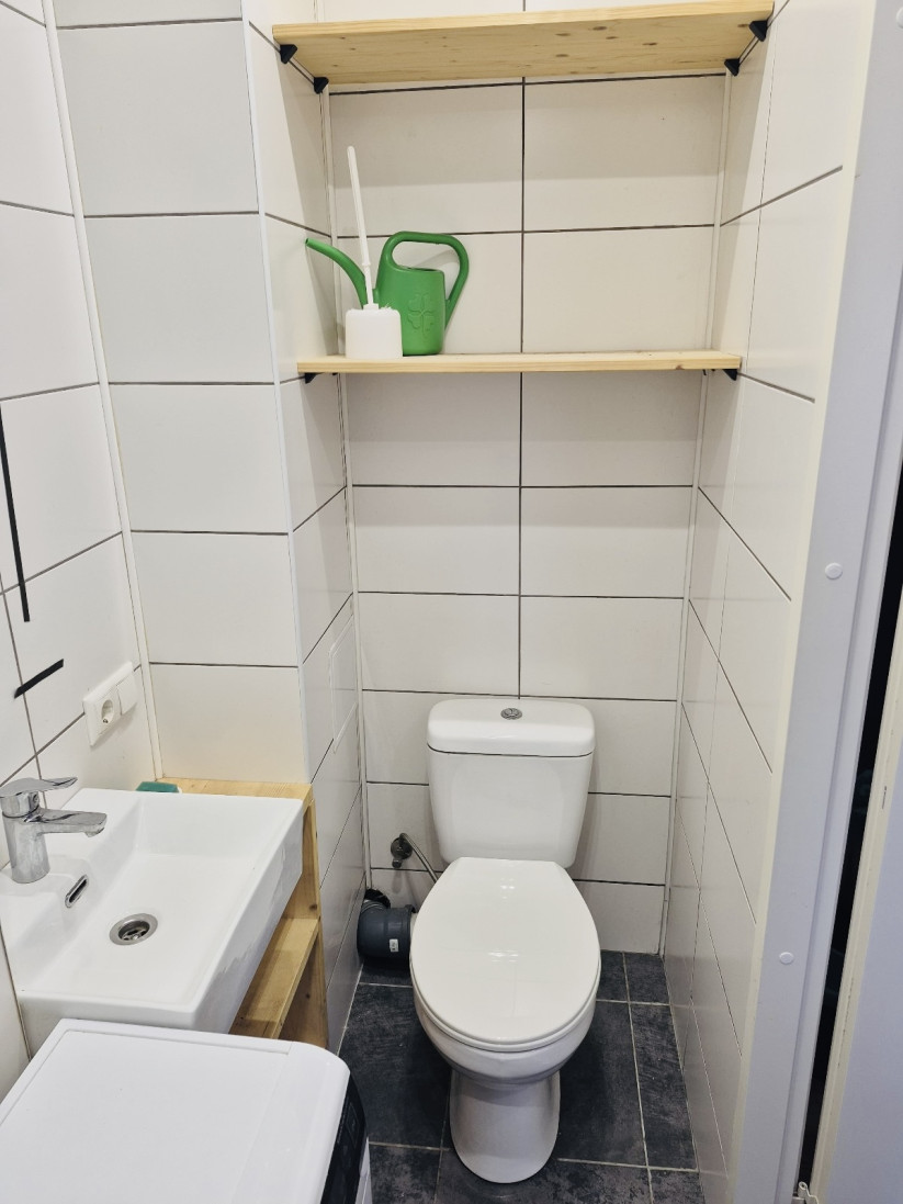 Kompakta tualete ar izlietni, plauktiem un veļasmašīnu.