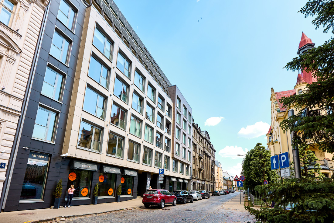 Modernas daudzdzīvokļu mājas fasāde ar stikla logiem.