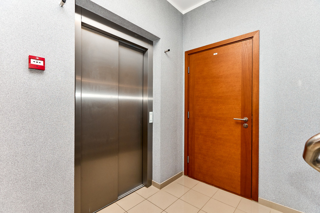 Elevator and wooden door in hallway.