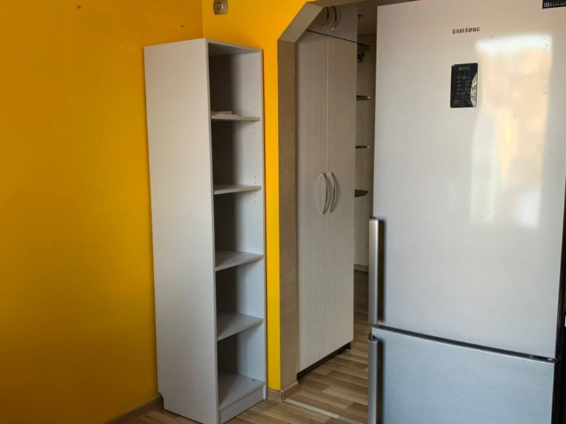 Kitchen area with fridge and shelf.