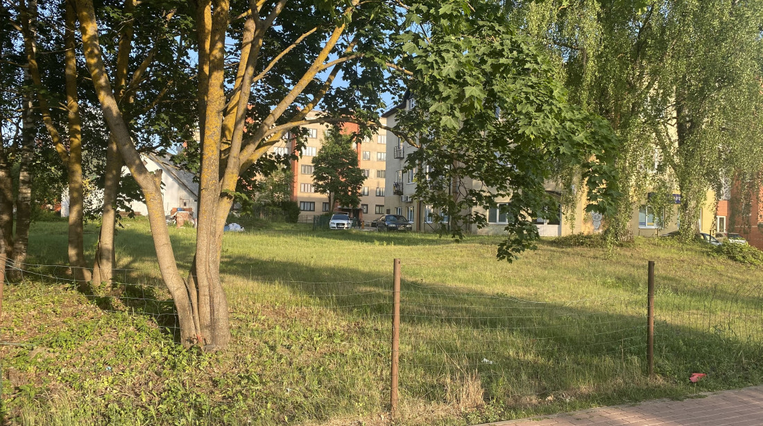 Nožogots zālājs ar kokiem un dzīvojamām mājām.