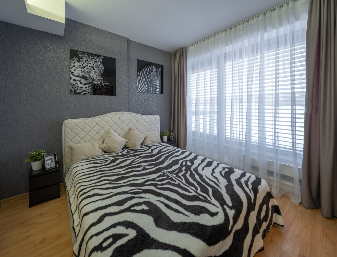 Bedroom with zebra-patterned blanket and window.