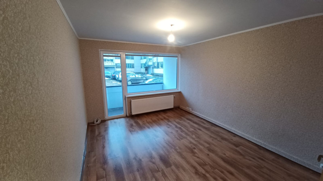 Spacious room with large window and radiator.