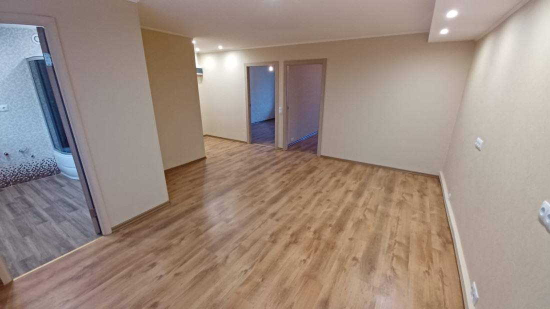 Living area with laminate flooring and multiple doors.