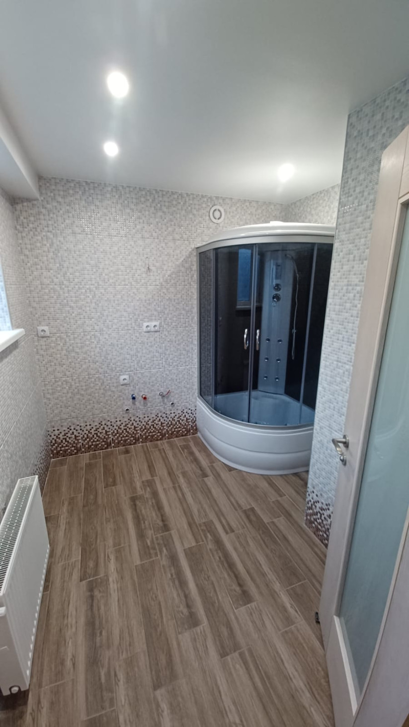 Bathroom with shower cabin and tiled walls.